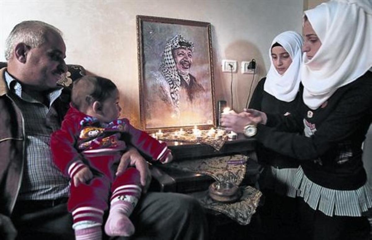 Una familia palestina enciende velas junto a un retrato de Yaser Arafat, el pasado 2 de noviembre, en Hebrón.