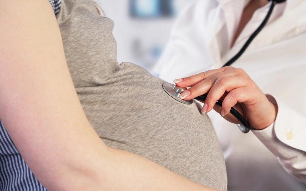 Un obstetra examina a una mujer embarazada.