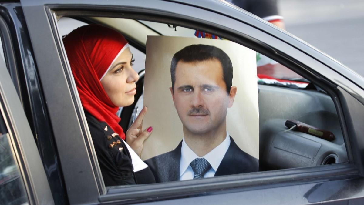Una mujer muestra el retrato de Bashar a-Asad en una celebración del aniversario del presidente sirio, en Damasco, en el 2013. Una mujer muestra el retrato de Bashar a-Asad en una celebración del aniversario del presidente sirio, en Damasco, en el 2013.