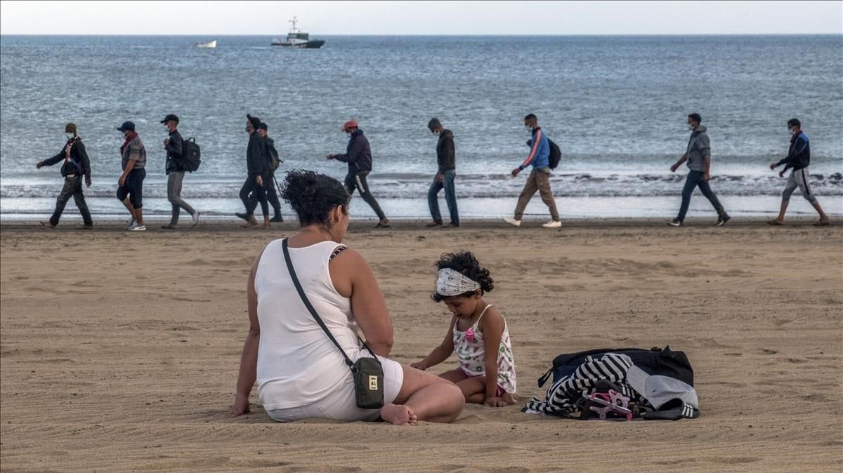Policías españoles escoltan a un grupo de inmigrantes marroquís en una playa canaria. Policías españoles escoltan a un grupo de inmigrantes marroquís en una playa canaria.