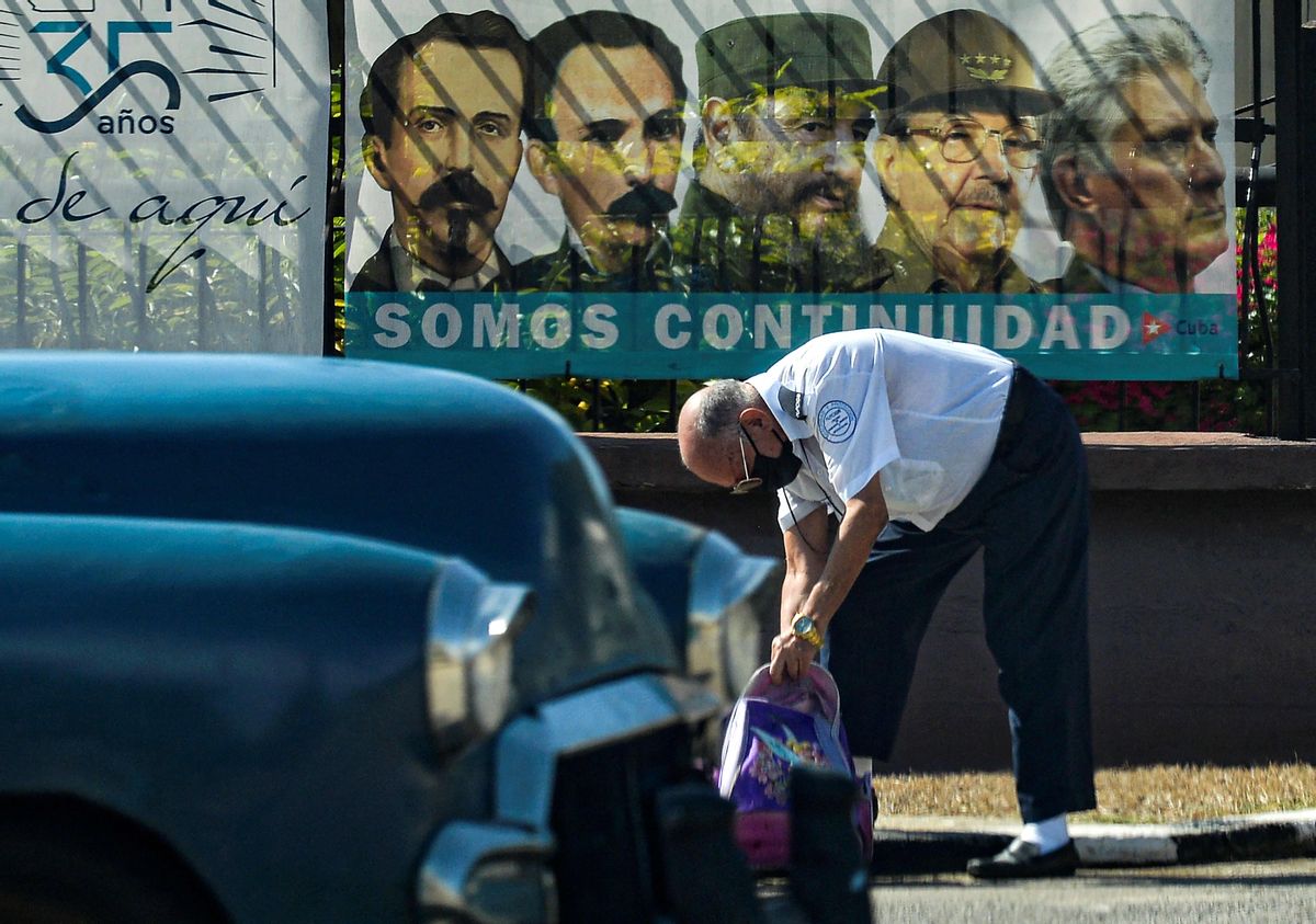 Un hombre con su coche frente al cartel del Partido Comunista cubano. Un hombre con su coche frente al cartel del Partido Comunista cubano.