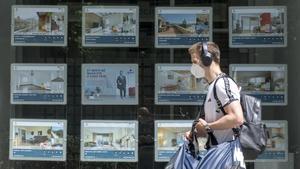 Un joven pasa por delante de una agencia inmobiliaria en el Eixample de Barcelona, este lunes.
