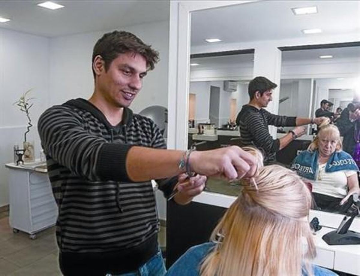 Un trabajador autónomo atiende a una clienta en su peluquería de Barcelona. Un trabajador autónomo atiende a una clienta en su peluquería de Barcelona.