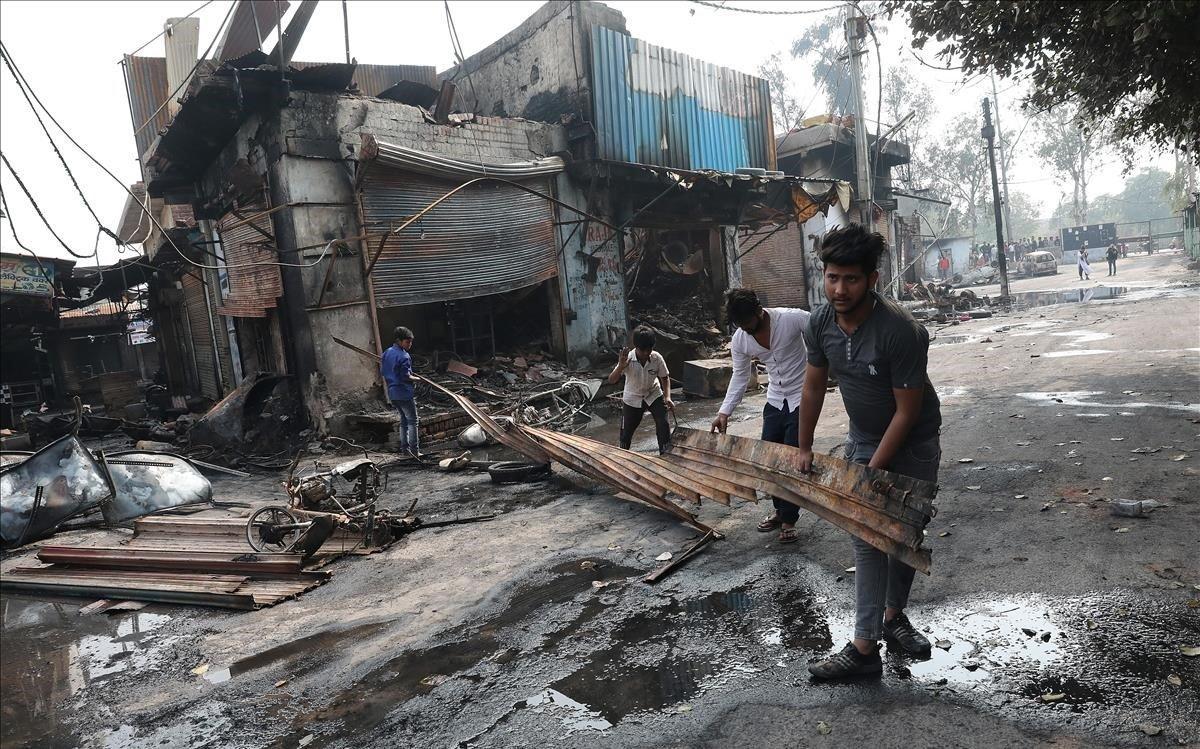 Varios hombres sacan material quemado de un edificio afectado por las protestas entre hindús y musulmanes en Nueva Deli, este miércoles.