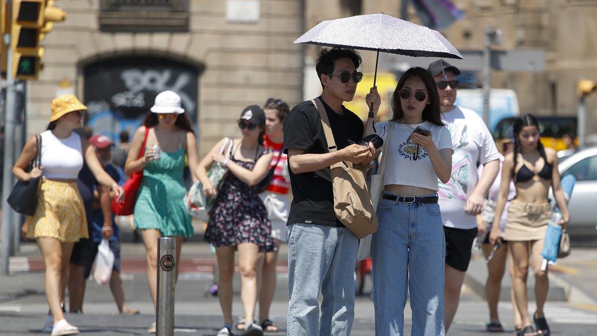  Unos turistas pasean por el centro de Barcelona, todas las comarcas de Cataluña entran en el máximo nivel de alerta por la ola de calor, que alcanza su pico con temperaturas que superarán los 41 °C en la ’plana’ de Lleida.