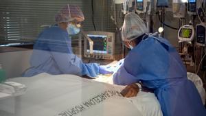Dos profesionales sanitarias del Hospital Clínic de Barcelona con un paciente ingresado en el Área de Vigilancia Intensiva.