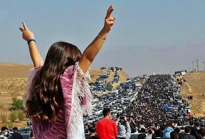 Una mujer sin velo en la parte superior de un vehículo mientras miles de personas se dirigen hacia el cementerio de Aichi en Saqez, la ciudad natal de Mahsa Amini en la provincia occidental iraní de Kurdistán, para conmemorar los 40 días desde su muerte.