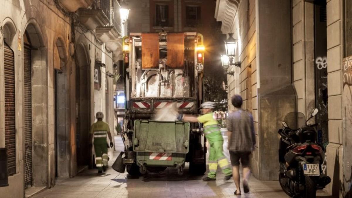 Operarios de limpieza vaciando un contenedor de basura en el distrito de Ciutat Vella, en Barcelona.