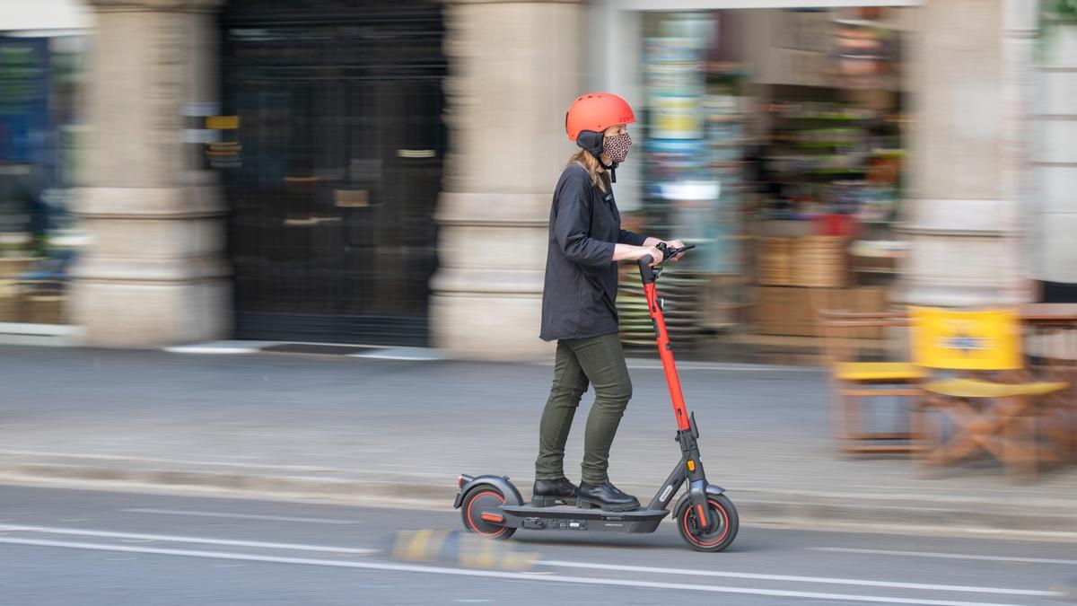 Una mujer circula en un patinete eléctrico por las calles de Barcelona