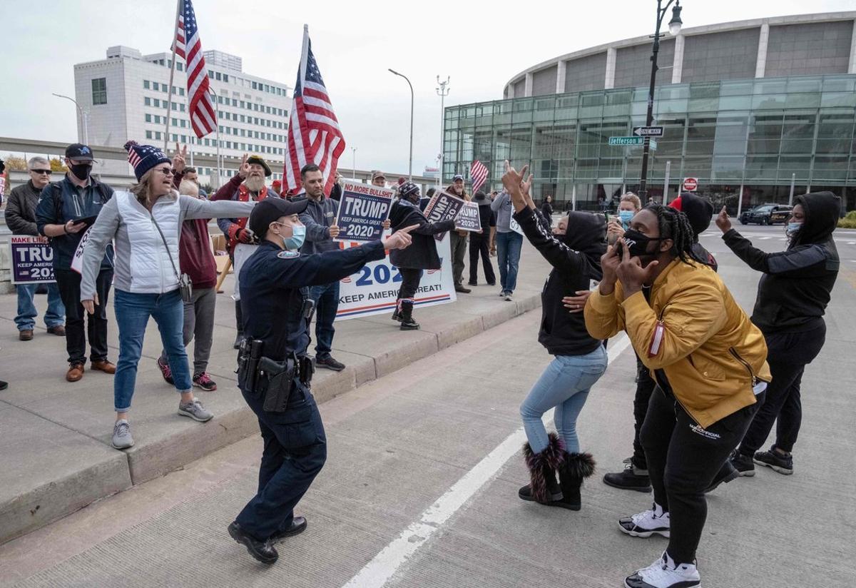 Counter protesters gesture at supporters of US President Donald Trump during demonstrations outside of the TCF Center in downtown Detroit, Michigan November 5, 2020. - Former vice president Joe Biden, making his third run at the White House, was tantalizingly close to victory as President Donald Trump sought to stave off defeat with scattershot legal challenges and his campaign insisted he would be reelected. (Photo by SETH HERALD / AFP)