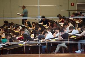 Alumnas y alumnos universitarios realizan un examen.