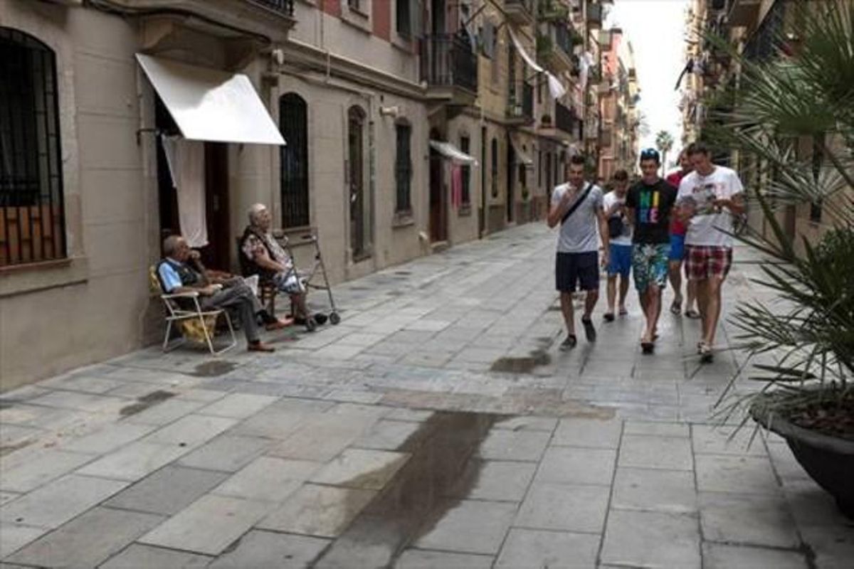 Dos vecinos tomando la fresca en la calle, símbolo del barrio, observan pasar a un grupo de turistas. Dos vecinos tomando la fresca en la calle, símbolo del barrio, observan pasar a un grupo de turistas.