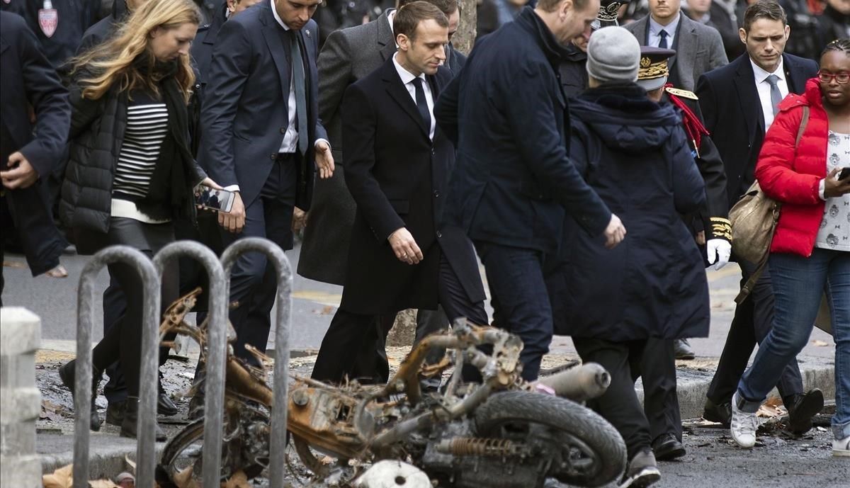 Emmanuel Macron pasa cerca de una motocicleta incendiada en los disturbios del pasado 1 de diciembre. Emmanuel Macron pasa cerca de una motocicleta incendiada en los disturbios del pasado 1 de diciembre.