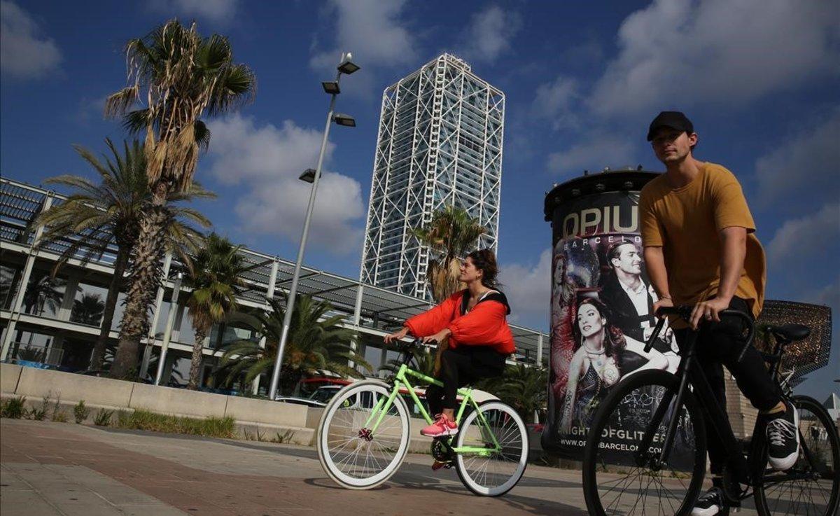 Dos ciclistas sin mascarilla circulan frente al Hotel Arts, hace unos días.