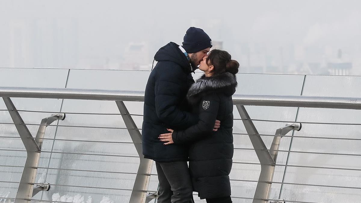 Una pareja se besa en un puente.