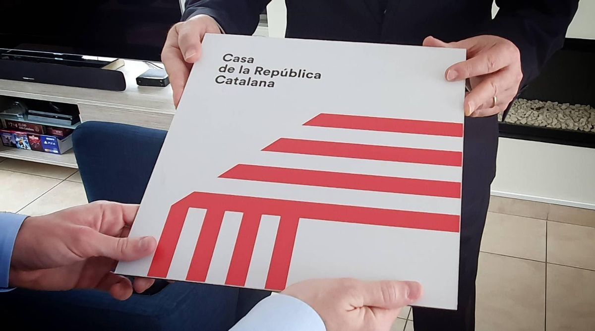 Momento en el que Puigdemont recupera la placa de su casa. Momento en el que Puigdemont recupera la placa de su casa.