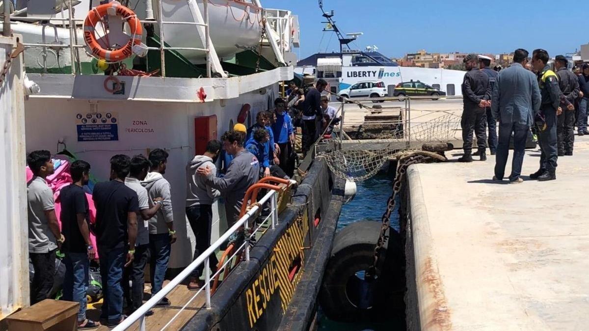 Varios inmigrantes rescatados en alta mar se disponen a desembarcar en el puerto italiano de Lampedusa.