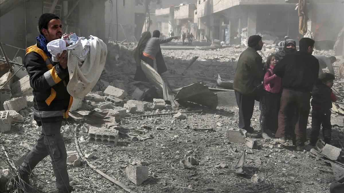 Un hombre lleva en brazos a un bebé rescatado entre las ruinas de un edificio tras el bombardeo de Guta por parte de las fuerzas del régimen de Damasco.