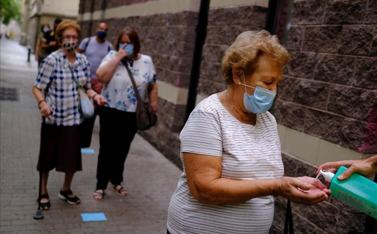 Una mujer se lava con gel hidroalcohólico antes de realizarse un test PCR en el Raval, Barcelona. Una mujer se lava con gel hidroalcohólico antes de realizarse un test PCR en el Raval, Barcelona.