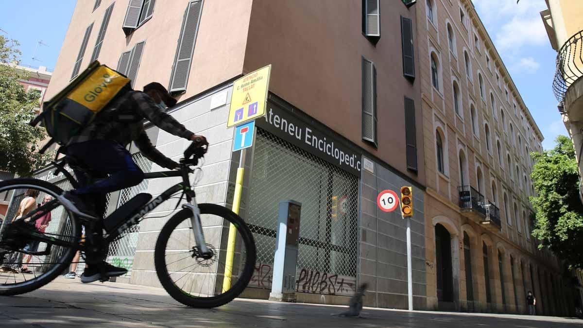 Un ’glovero’, máximo exponente de la precariedad de la clase trabajadora en el siglo XXI, pasa frente al flamante local del Ateneu Enciclopèdic Popular en el Raval Un ’glovero’, máximo exponente de la precariedad de la clase trabajadora en el siglo XXI, pasa frente al flamante local del Ateneu Enciclopèdic Popular en el Raval