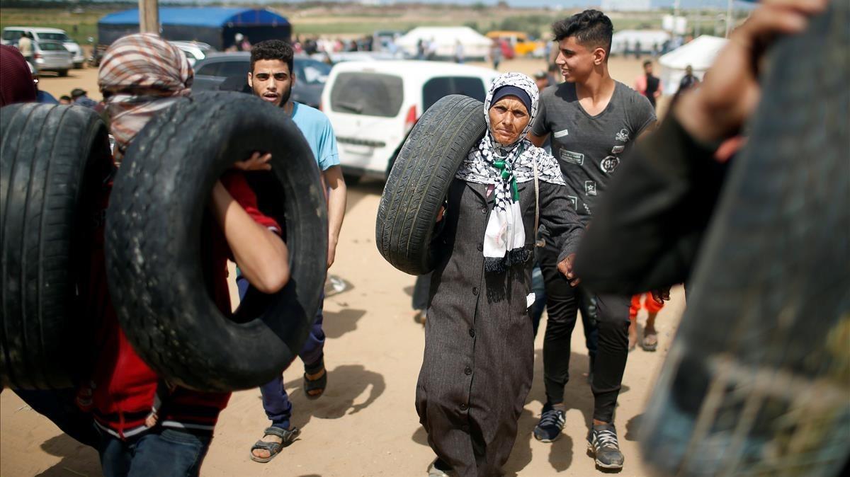 Manifestantes palestinos cargan con neumáticos mientras se preparan para las protestas en la frontera entre Gaza e Israel este lunes 14 de mayo.