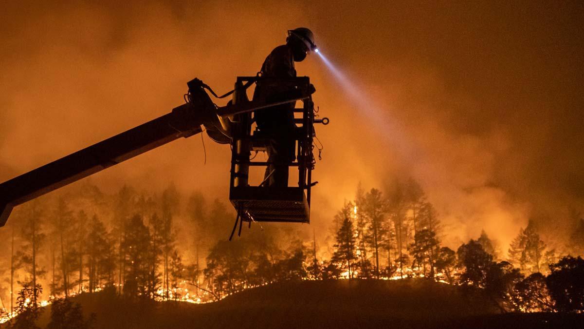 25 muertos y miles de evacuados por los incendios de California. En la foto, un empleado de una compañía de comunicaciones trabaja en la instalación de fibra óptica en una zona afectada por el incendio, en Calistoga (California).