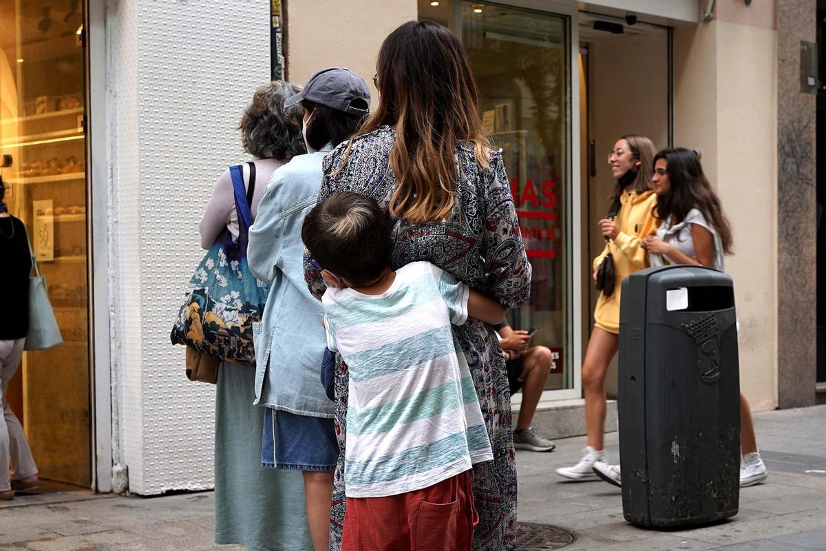 Un niño abraza a su madre mientras esperan para entrar en un comercio, en Madrid.