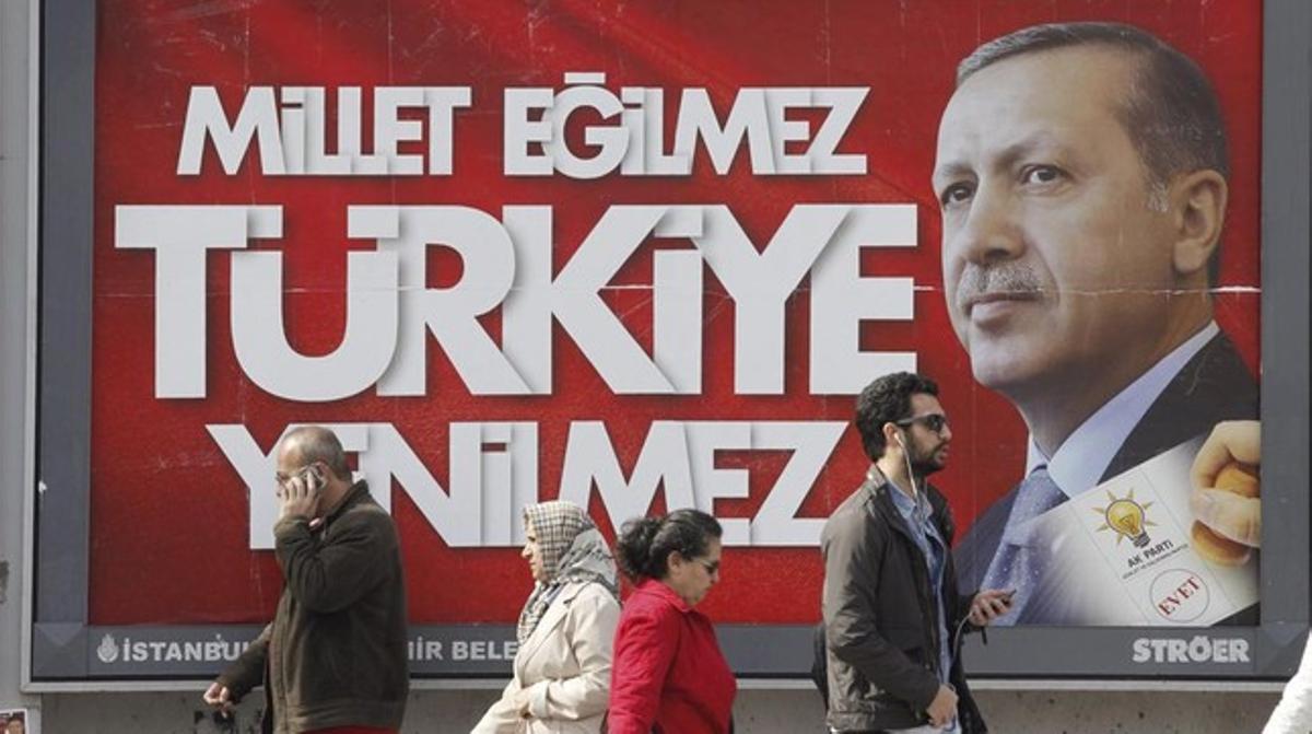 Varias personas pasan por delante de un cartel electoral de Erdogan, este jueves en Estambul.