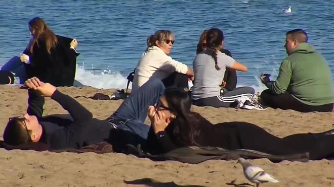 Visitantes ya abrigados en las playas de Barcelona, en un día de temperatura otoñal
