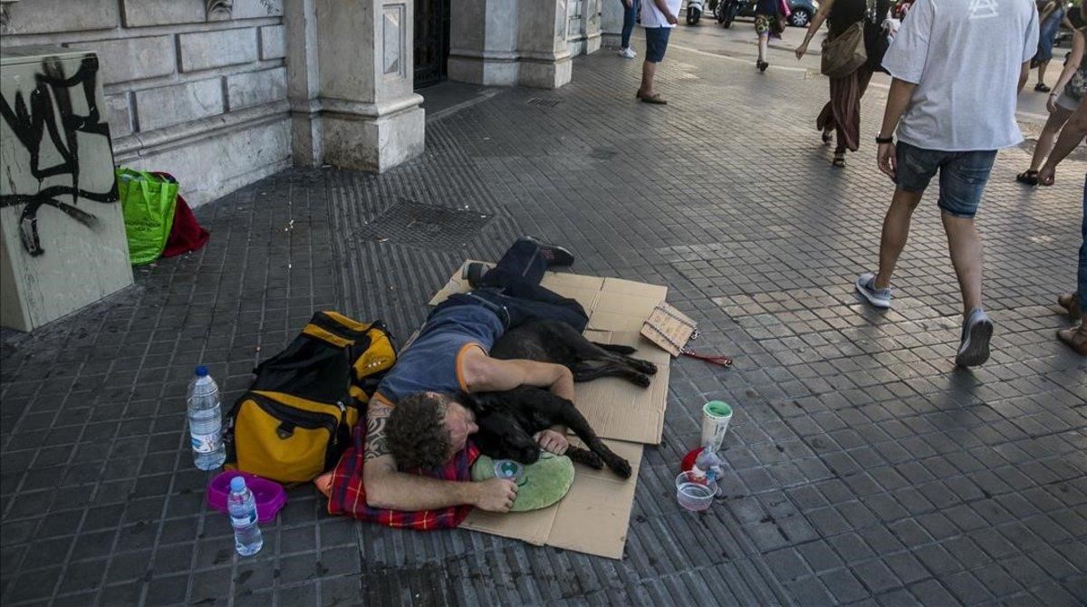 Un sintecho duerme en plena calle en la Rambla de Catalunya con Plaza de Catalunya. Un sintecho duerme en plena calle en la Rambla de Catalunya con Plaza de Catalunya.