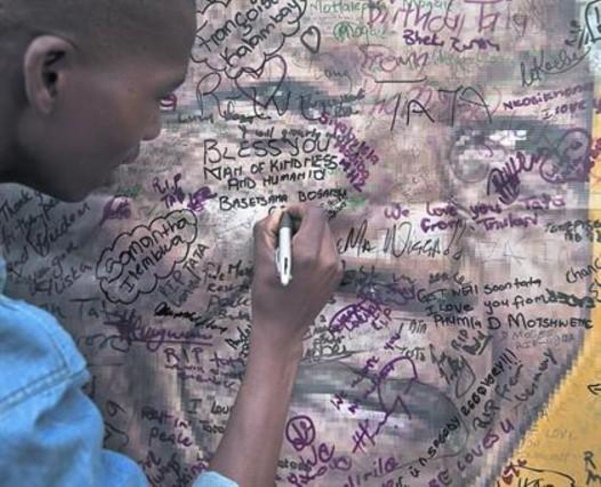 Un vecino de Soweto firma una condolencia en un póster en las afueras de la vieja casa de Mandela. Un vecino de Soweto firma una condolencia en un póster en las afueras de la vieja casa de Mandela.