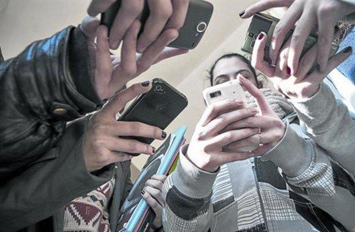 Unos alumnos de secundaria consultan sus móviles a salida de clase. Unos alumnos de secundaria consultan sus móviles a salida de clase.