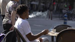 Un joven fuma en una terraza de Sant Antoni, en Barcelona.