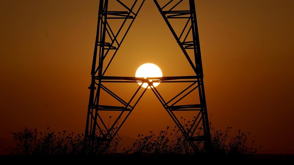 Una torre de electricidad con el sol de fondo.