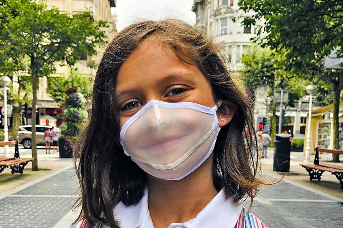 Una niña con un modelo de mascarilla higiénicas transparente reutilizable Biovest Expression.