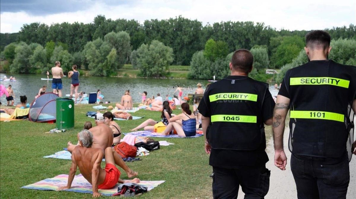 Dos agentes de seguridad vigilan que los bañistas cumplan la distancia de seguridad en Neckartailfingen, en el sur de Alemania. Dos agentes de seguridad vigilan que los bañistas cumplan la distancia de seguridad en Neckartailfingen, en el sur de Alemania.