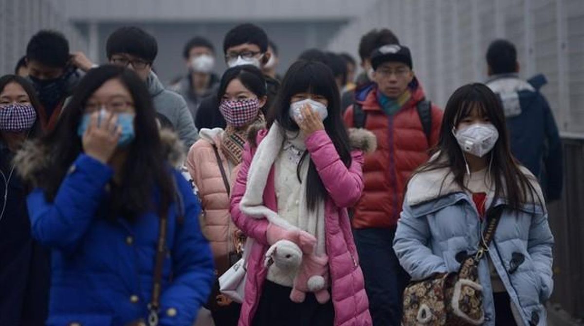 Un grupo de peatones cruza las calles de Pekín protegidos con máscaras Un grupo de peatones cruza las calles de Pekín protegidos con máscaras