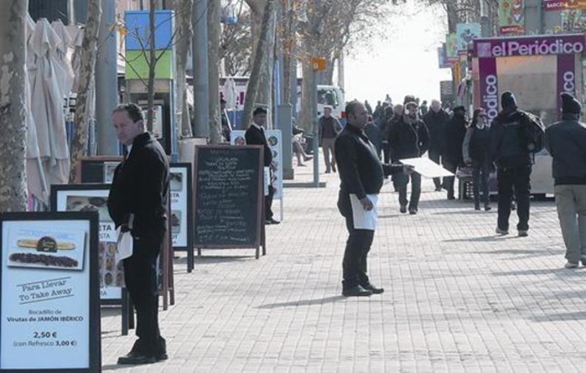 Un camarero de un restaurante de la Barceloneta busca clientes en la calle.