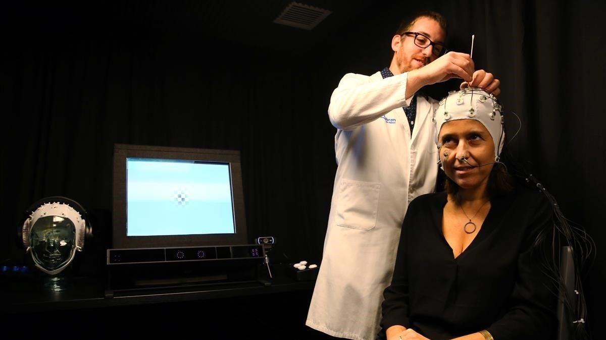Un médico del Migraine Adaptive Brain Center coloca un gorro de encefalografía a una paciente, este jueves. Un médico del Migraine Adaptive Brain Center coloca un gorro de encefalografía a una paciente, este jueves.