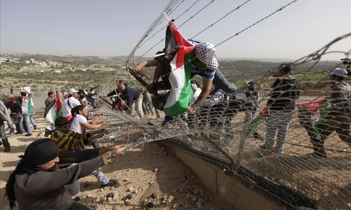 Manifestantes palestinos tratan de derribar una sección de la controvertida barrera israelí durante una protesta en la aldea de Bilin, cerca de Ramala, en Cisjordania. Manifestantes palestinos tratan de derribar una sección de la controvertida barrera israelí durante una protesta en la aldea de Bilin, cerca de Ramala, en Cisjordania.