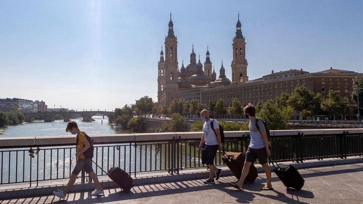 Personas con maletas cruzan el Puente de Santiago de Zaragoza, el pasado día 15. Personas con maletas cruzan el Puente de Santiago de Zaragoza, el pasado día 15.