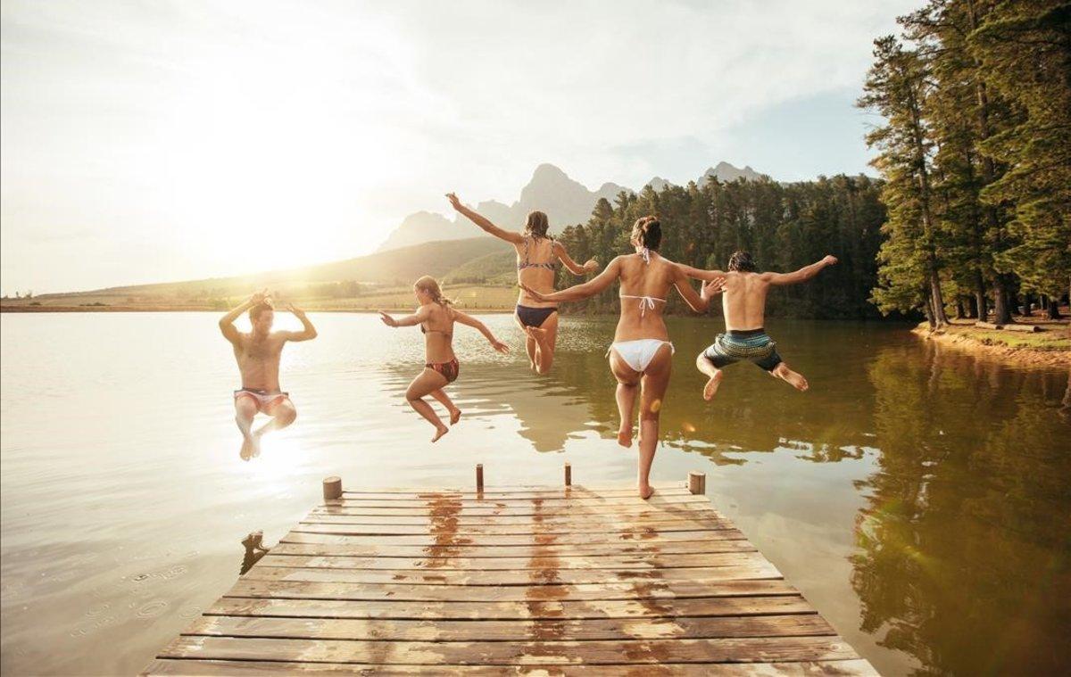 Un grupo de jóvenes saltando a un lago.