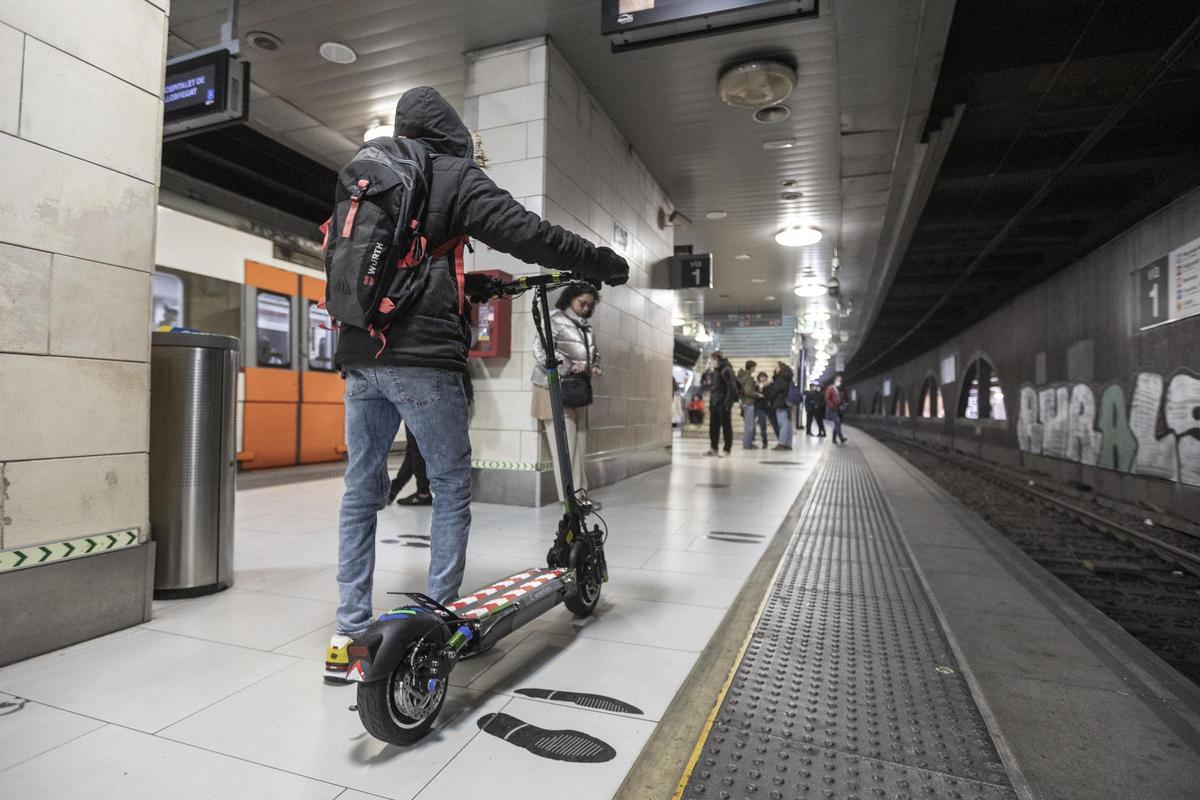 Un pasajero con un patinete eléctrico en la estación de Rodalies de plaza Catalunya, en Barcelona.