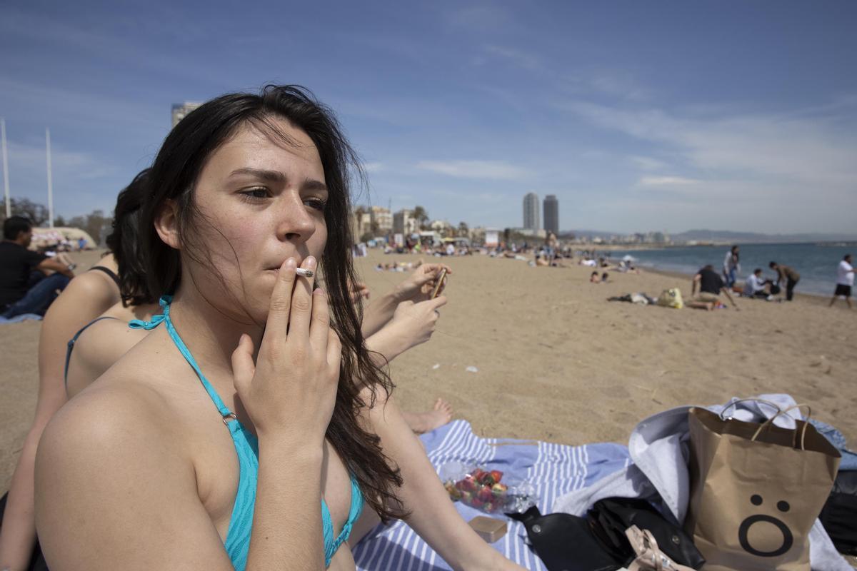 Una mujer fumando un cigarrillo en la playa de la Barceloneta, este mediodía.