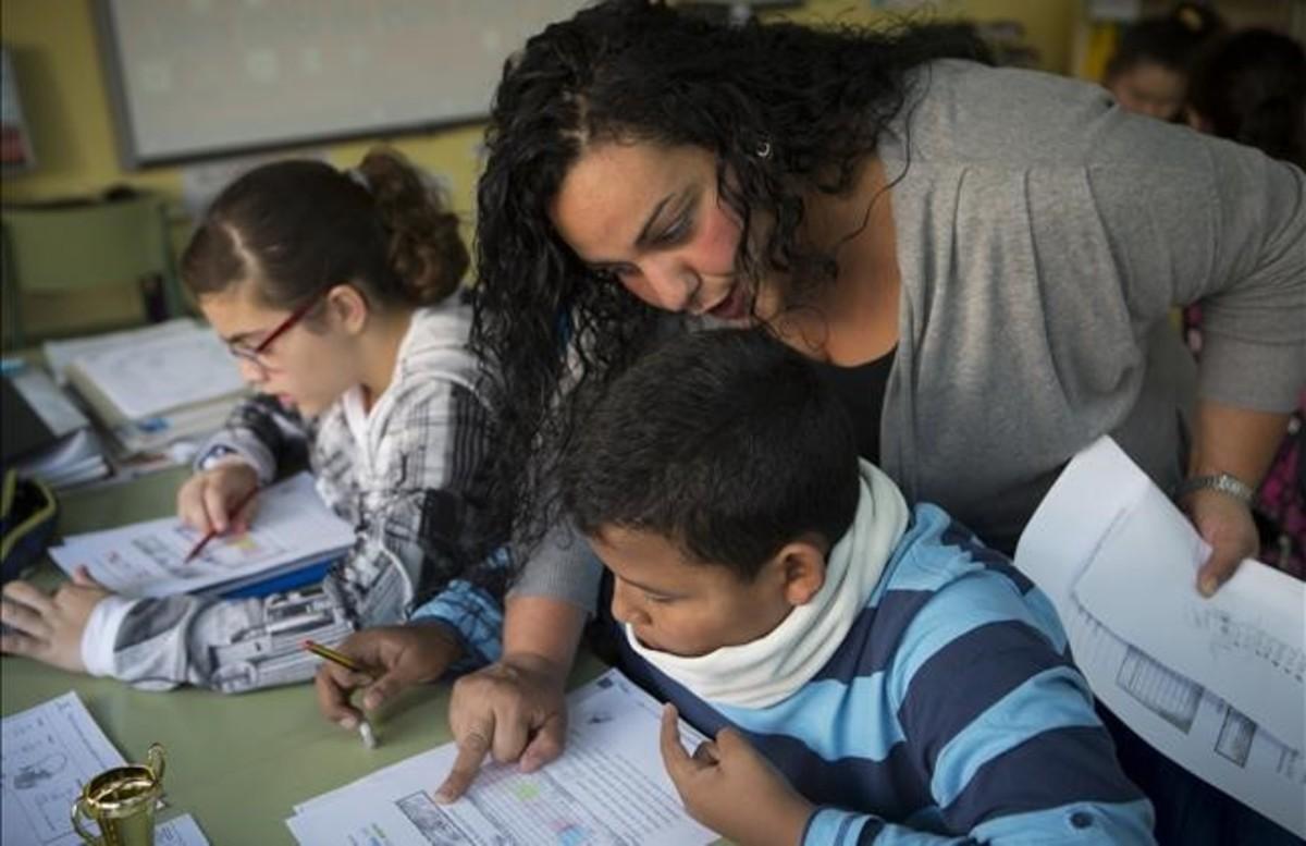 Una madre del colegio Joaquim Ruyra de L’Hospitalet ayuda como voluntaria a un alumno de sexto de primaria en una clase de Matemáticas.