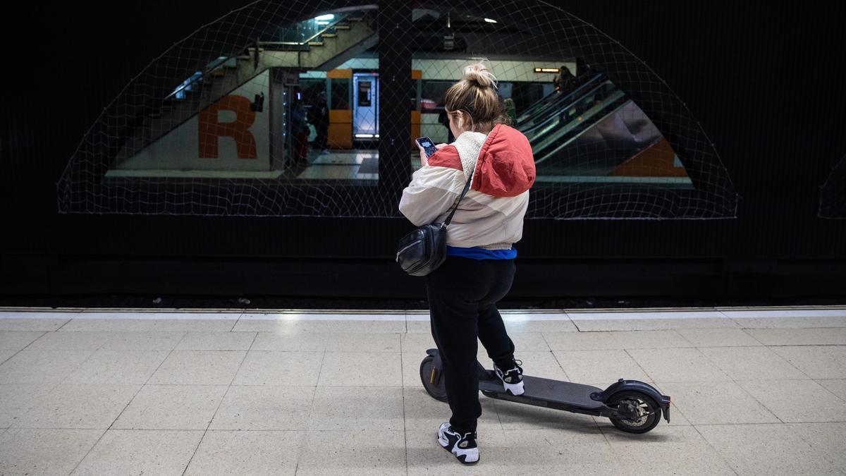 Una usuaria con patinete eléctrico en el transporte público.