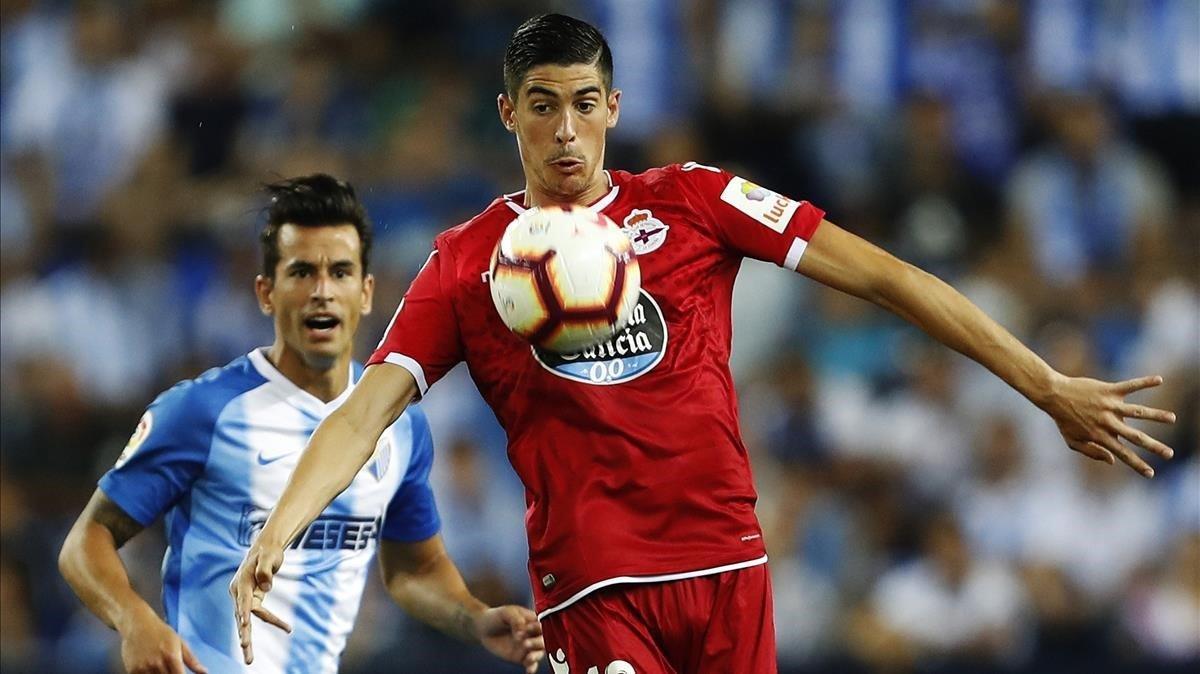 Carlos Fernández, del Depor, controla el balón presionado por Luis Hernández, del Málaga.