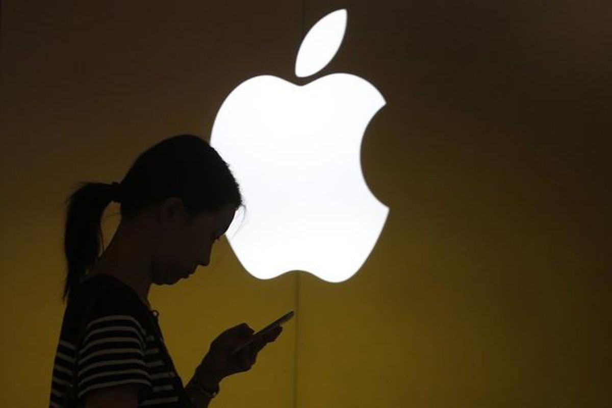 Una mujer mira su teléfono ante el logo de Apple en la tienda oficial de Shangai, China. Una mujer mira su teléfono ante el logo de Apple en la tienda oficial de Shangai, China.