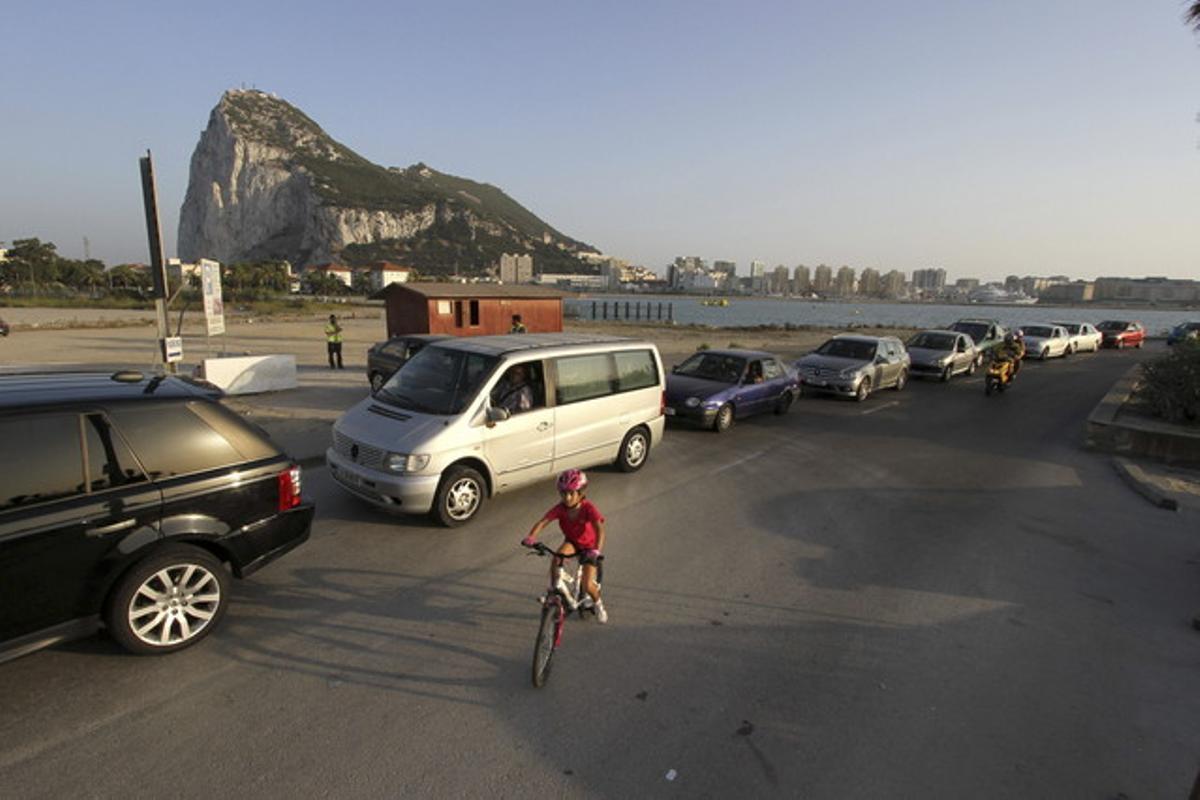 Un niño pasea con su bicicleta junto a una cola de coches para entrar a Gibraltar, en agosto pasado.