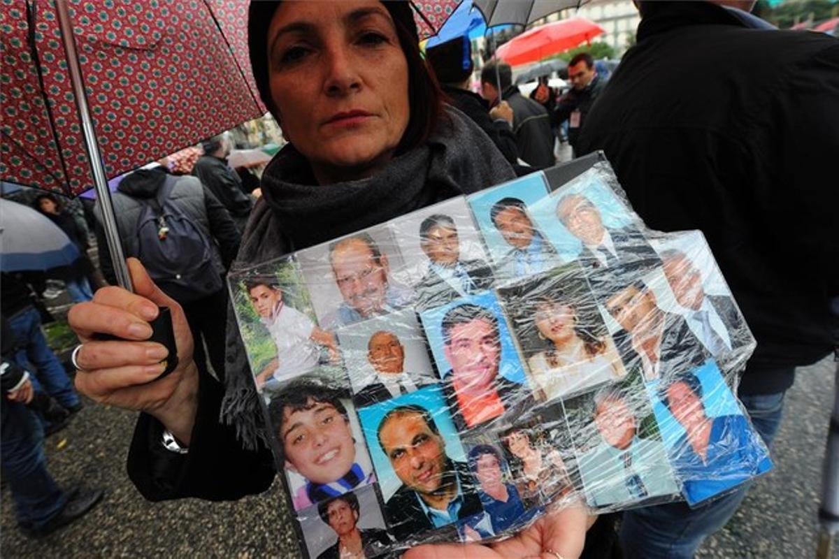 Una mujer muestra fotos de familiares y amigos muertos de cáncer, en Nápoles.